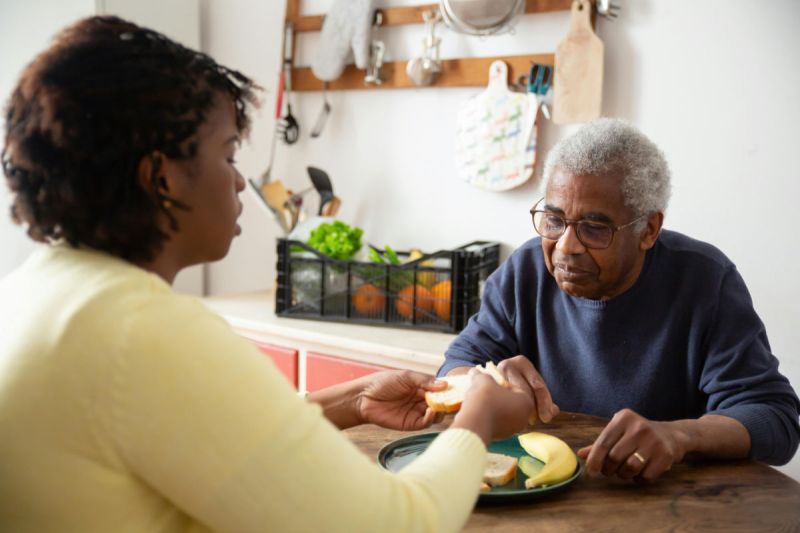 A caregiver is preparing a meal for senior man.