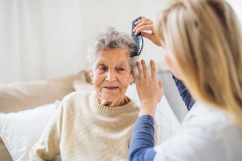 Senior care services in Atlanta with senior at home brushing her hair.